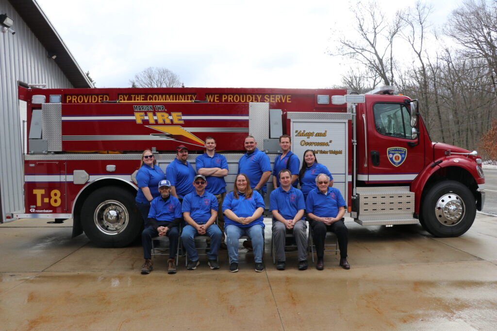 Fire department team posing with fire truck.